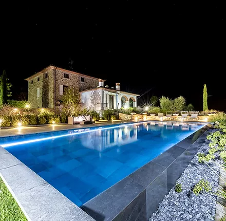Piscina privata con un lato a cascata Infinity e rivestimento in pietra, realizzata in Toscana Piscina privata con un lato a cascata Infinity e rivestimento in pietra, realizzata in Toscana