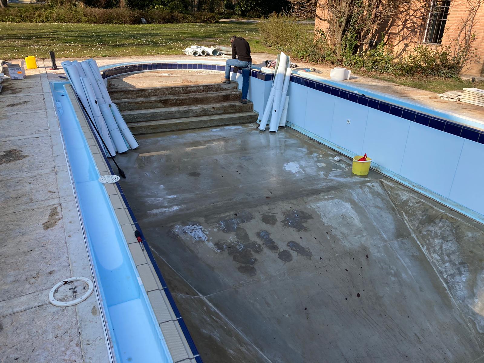 Piscina a sfioro con scala romana e cornice in mosaico, sottoposta a lavorazioni di ristrutturazione - senza rivestimento